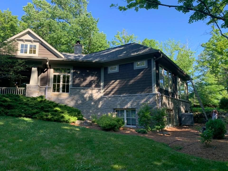 A large house with a lot of windows is surrounded by trees and grass.