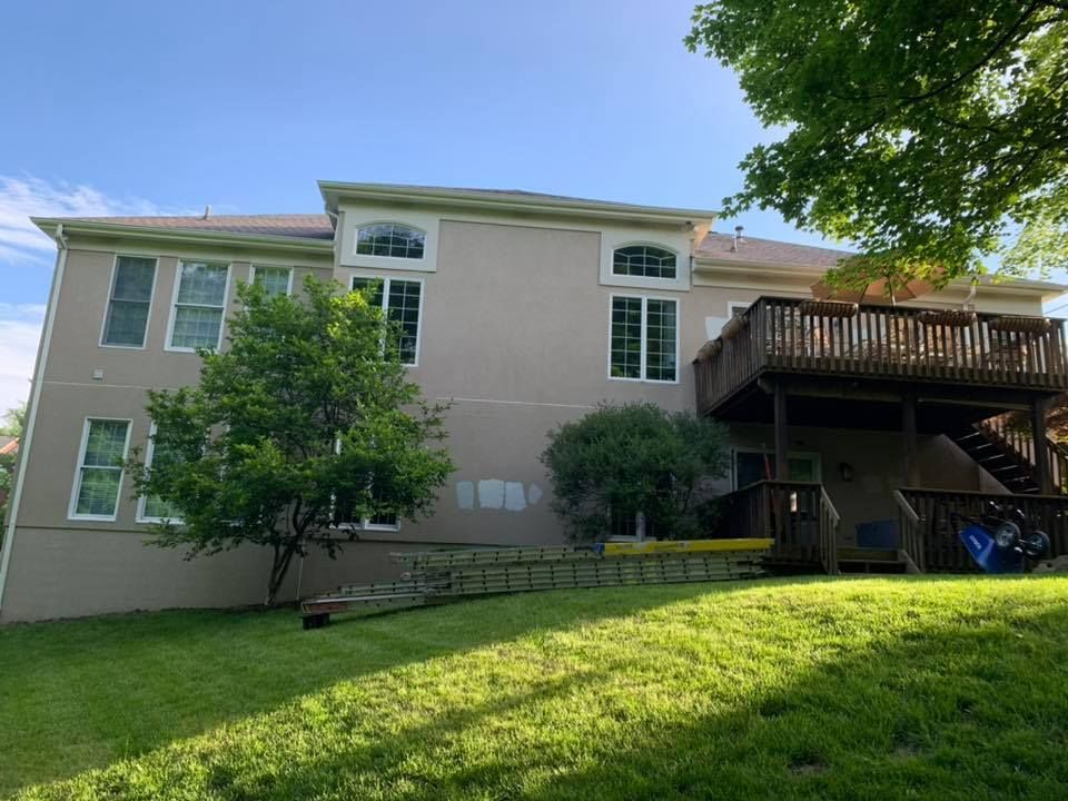 The back of a large house with a deck and stairs.