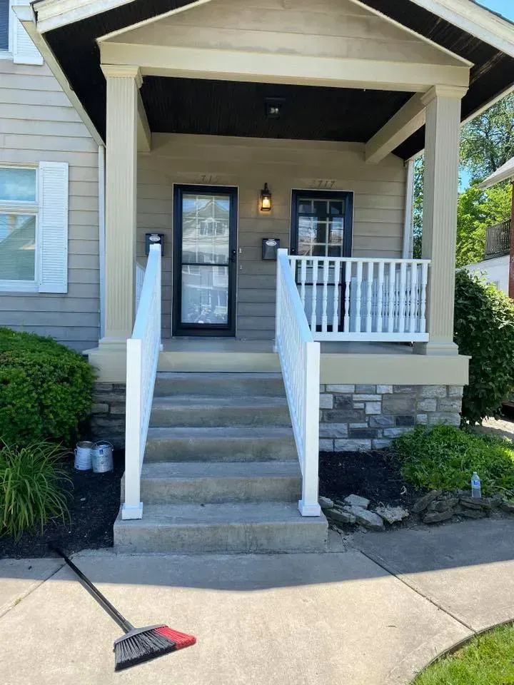 A broom is sitting on the sidewalk in front of a house.