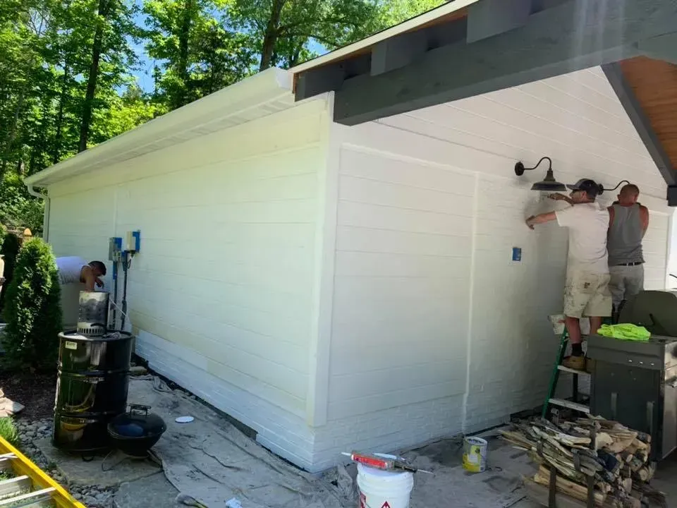 Two men are painting the side of a house.