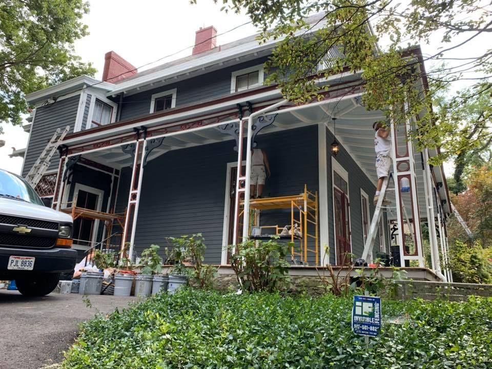 A man is painting the porch of a house.