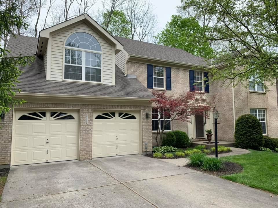 A large brick house with two white garage doors and blue shutters