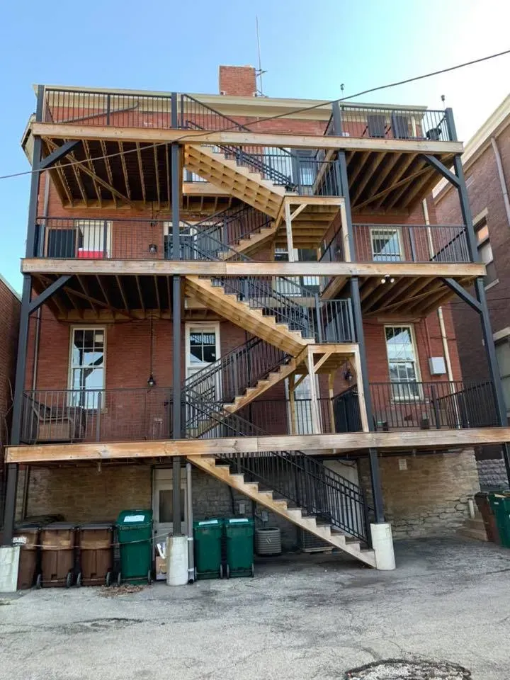 A large brick building with wooden stairs on the side of it.