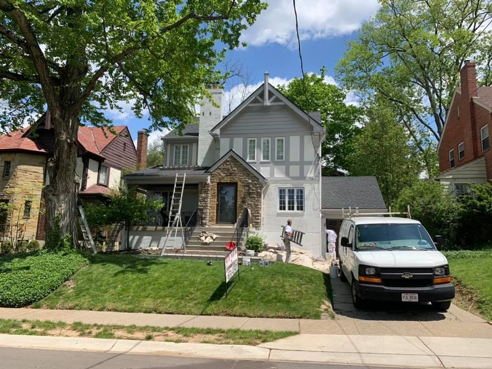 A white van is parked in front of a house that is being painted.