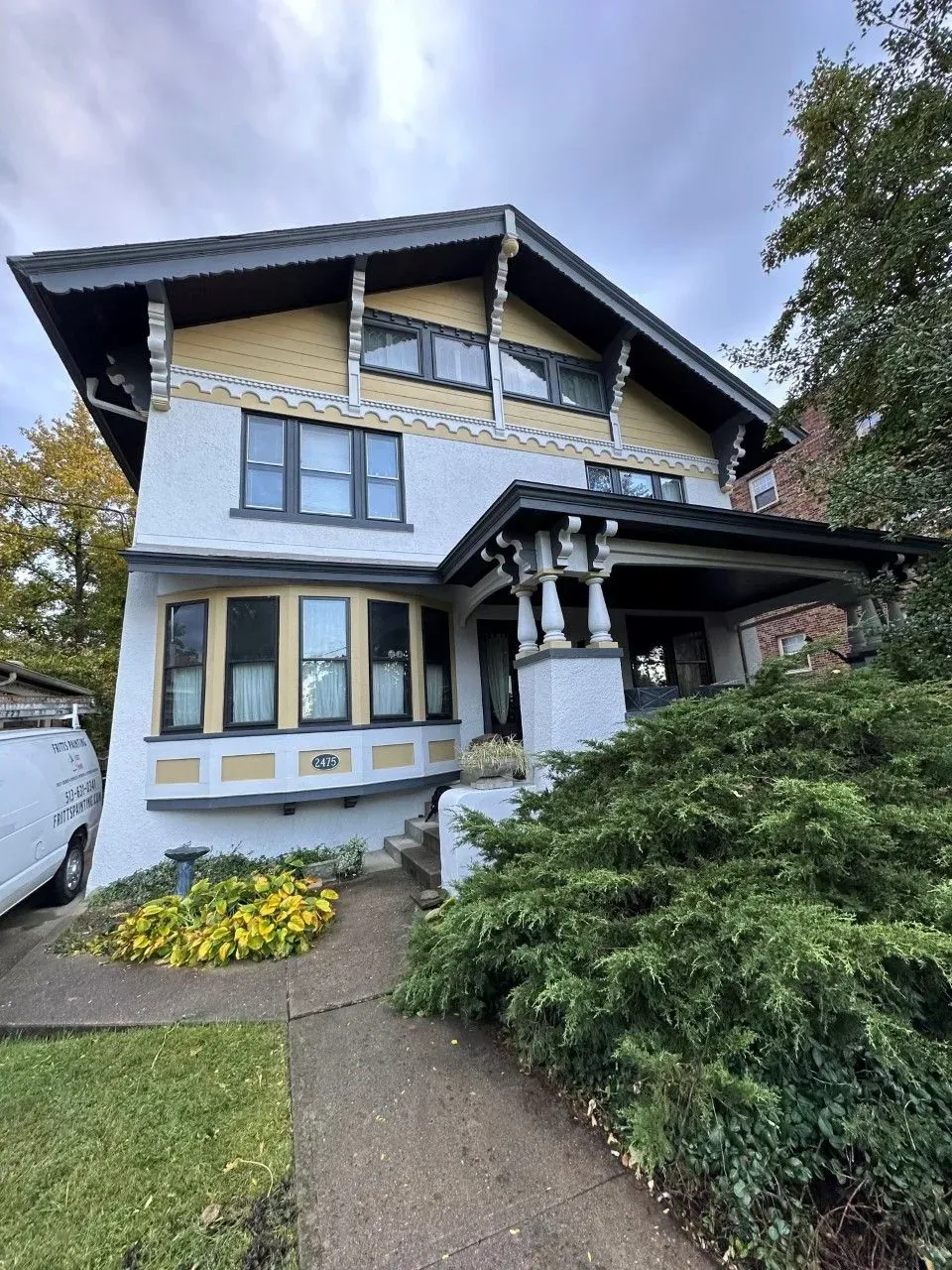A white and yellow house with a white van parked in front of it.