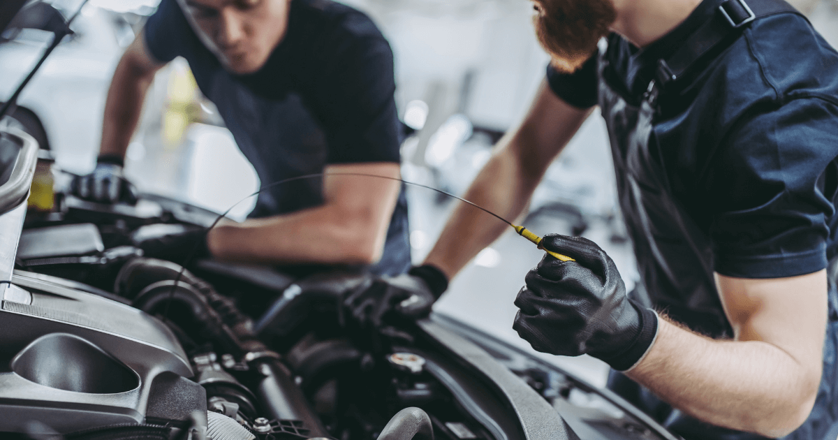 Two mobile mechanics looking under the hood of a car.