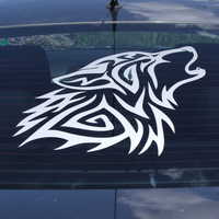 A sticker on the back window of a car shows a wolf howling