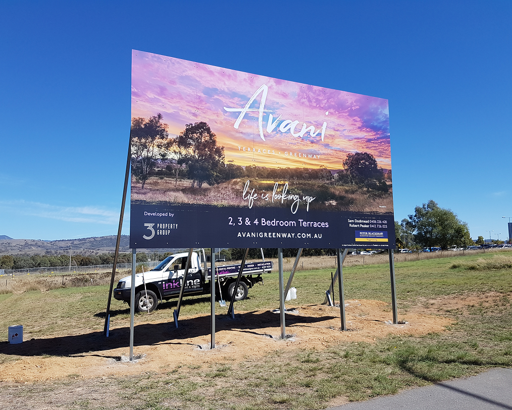 A large billboard is sitting in the middle of a field next to a truck. A large billboard is sitting in the middle of a field next to a truck.