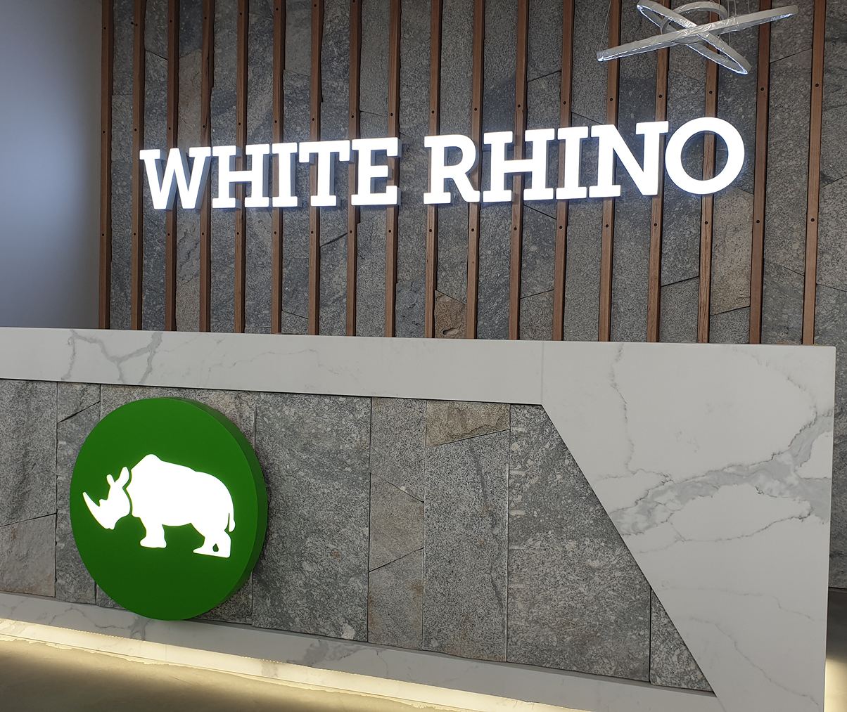 A white rhino sign is above a green circle with a rhino on it A white rhino sign is above a green circle with a rhino on it
