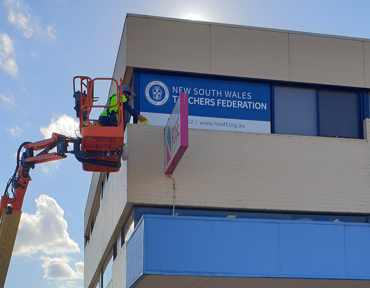 A crane is lifting a sign on the side of a building. A crane is lifting a sign on the side of a building.