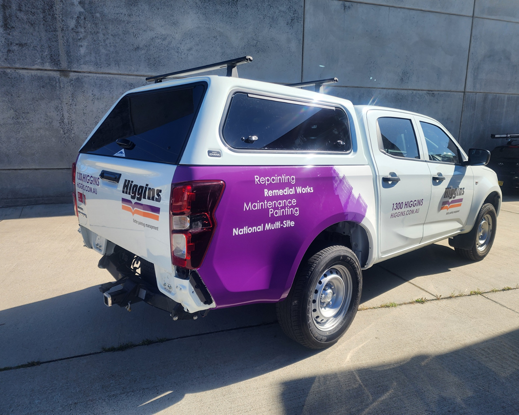A white truck with a purple canopy is parked on the side of the road. A white truck with a purple canopy is parked on the side of the road.