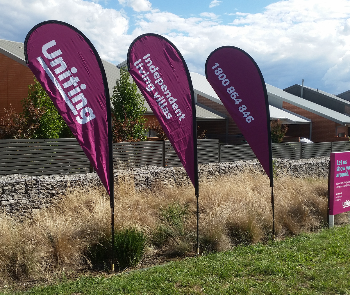 Three teardrop shaped flags with the word uniting on them Three teardrop shaped flags with the word uniting on them