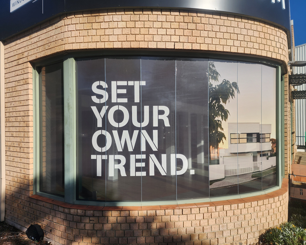 A sign on a brick building says `` set your own trend ''. A sign on a brick building says `` set your own trend ''.