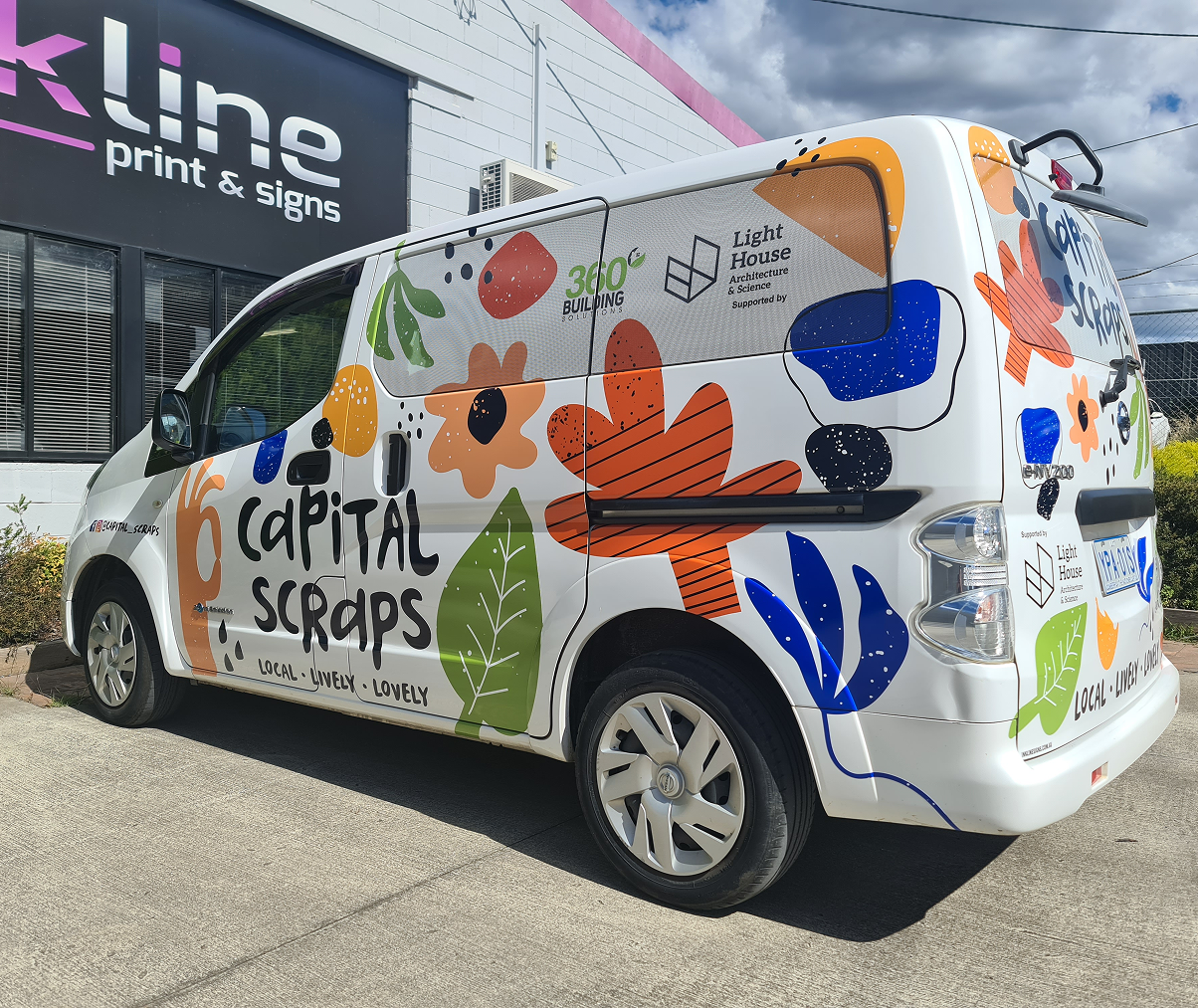 A white van with flowers and leaves painted on it is parked in front of a building. A white van with flowers and leaves painted on it is parked in front of a building.