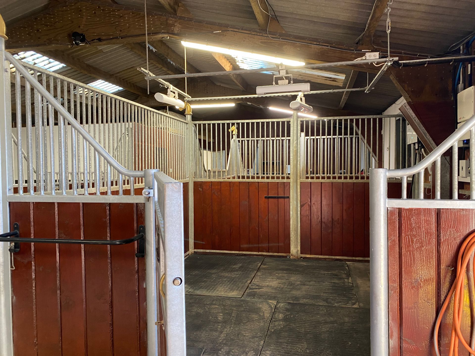 Horse stable interior with stalls, wooden doors, and metal railings.