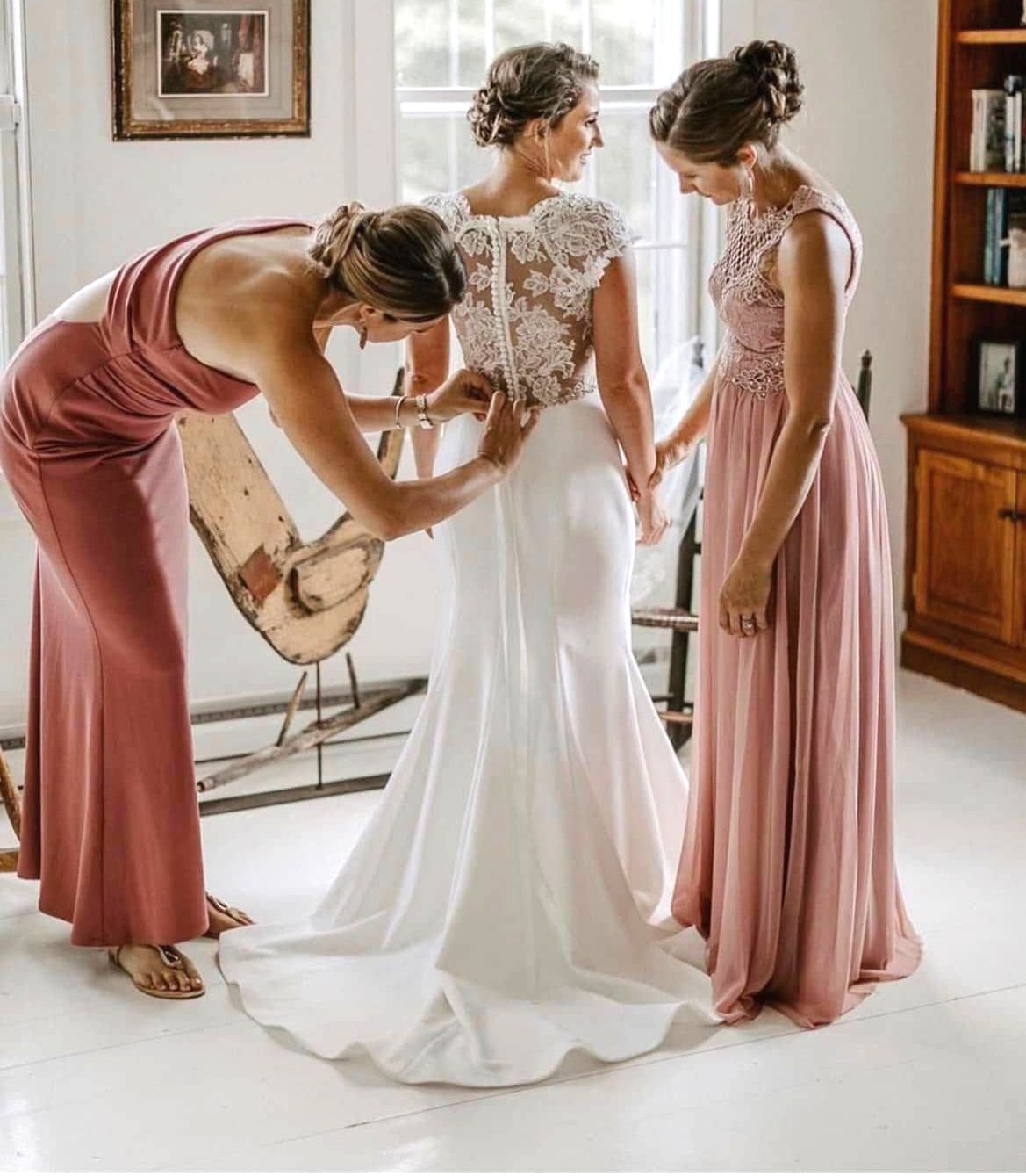 Woman having makeup applied; white robe, updo, smiling artist, light blue wall.