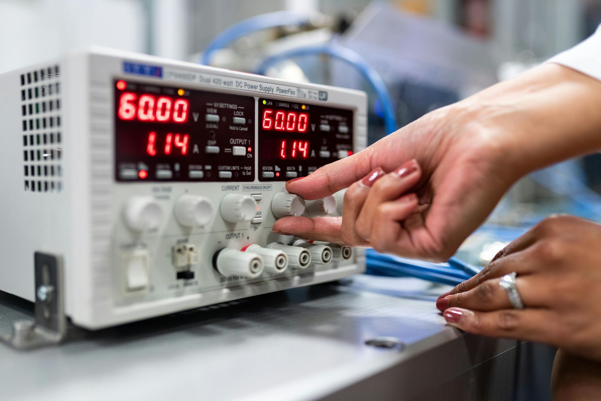 A woman is using a digital oscilloscope to measure voltage.