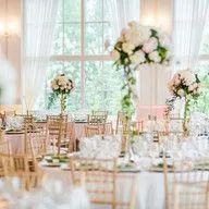 A room filled with tables and chairs set up for a wedding reception.