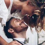 A bride and groom are kissing each other on the forehead.