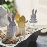 A bowl of cupcakes with bunny and chick cupcake toppers.