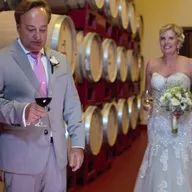 A bride and groom are standing next to each other in a wine cellar.