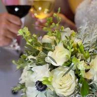 A bride is holding a glass of wine and a bouquet of flowers.