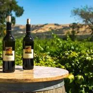 Two bottles of wine are sitting on top of a wooden barrel.