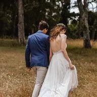 A bride and groom are walking through a field.