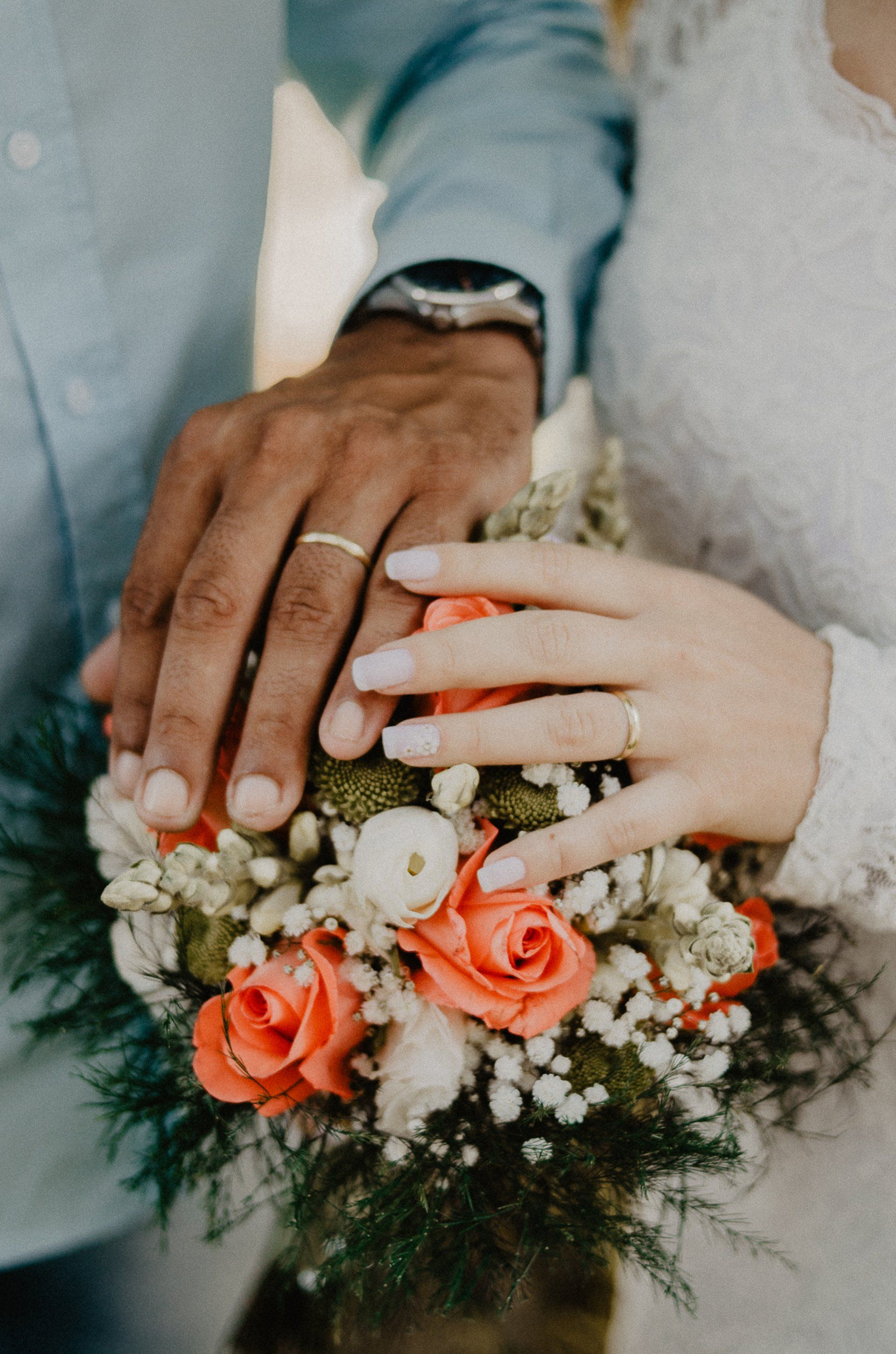 A close up of a bride and groom holding a bouquet of flowers.