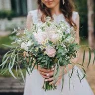 A bride in a white dress is holding a bouquet of flowers.