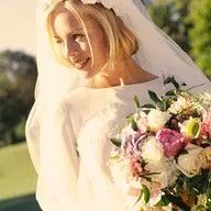 A bride in a wedding dress and veil is holding a bouquet of flowers.