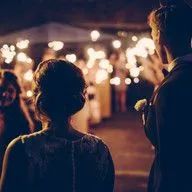 A bride and groom are standing in front of sparklers at a wedding reception.