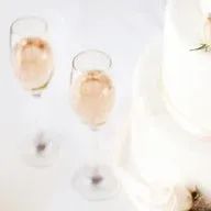Three glasses of champagne are sitting on a table next to a cake.