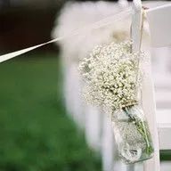 A vase filled with baby 's breath is hanging on a chair.