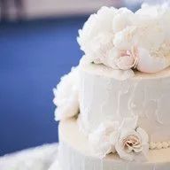 A white wedding cake with white flowers on top is sitting on a table.