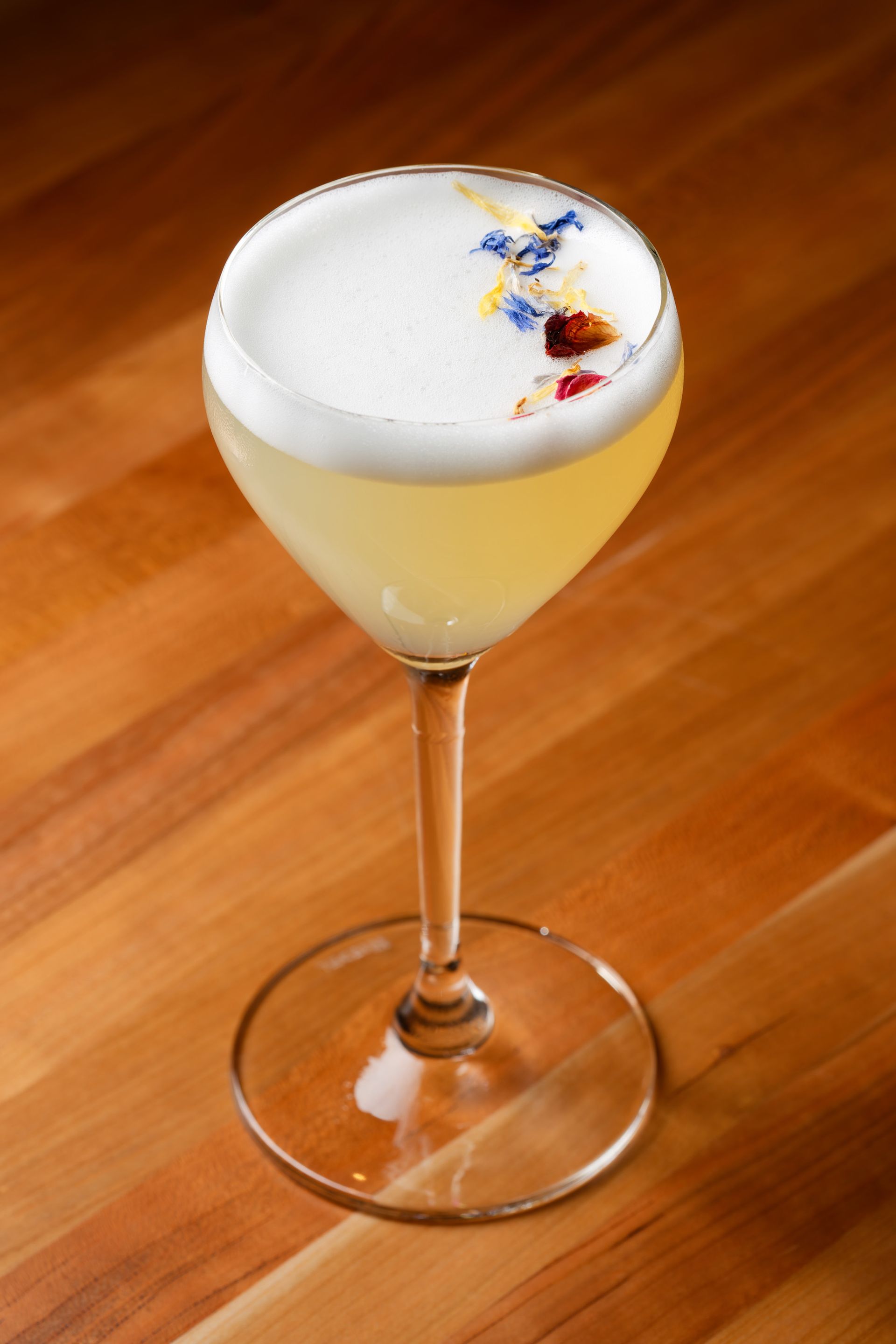 A close up of a cocktail in a wine glass on a wooden table