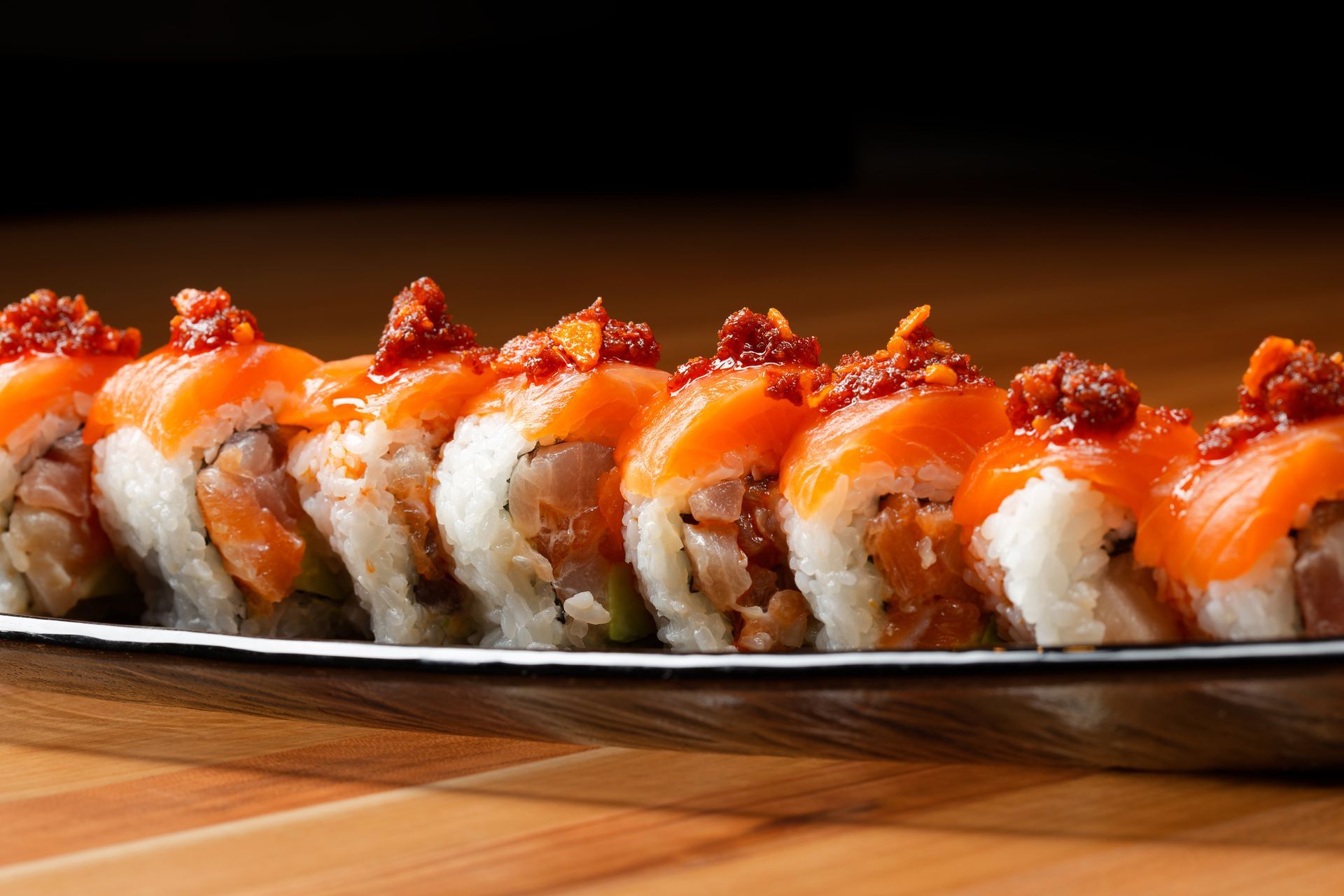 A close up of a plate of sushi on a wooden table.