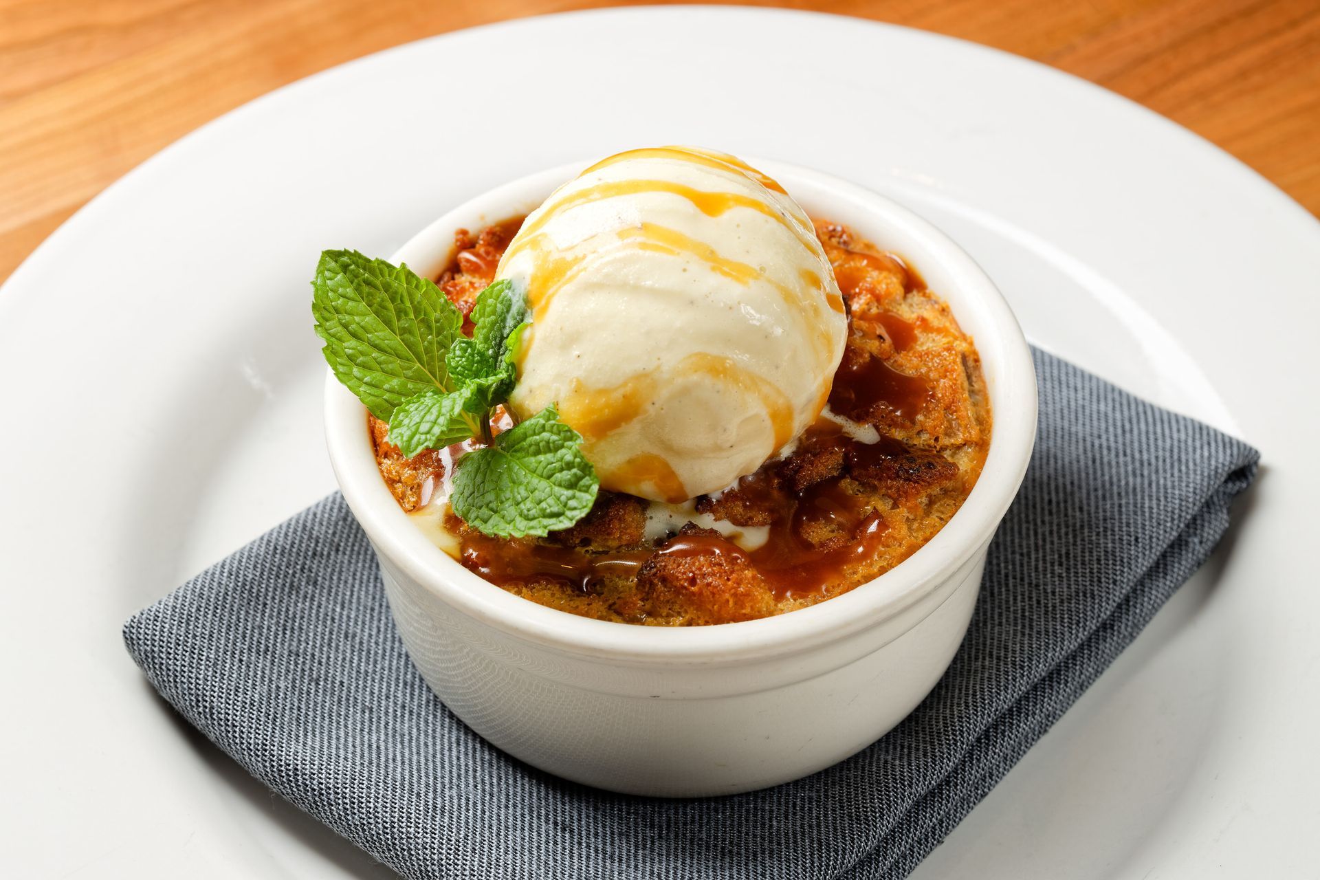 A white plate topped with a dessert with ice cream and mint leaves