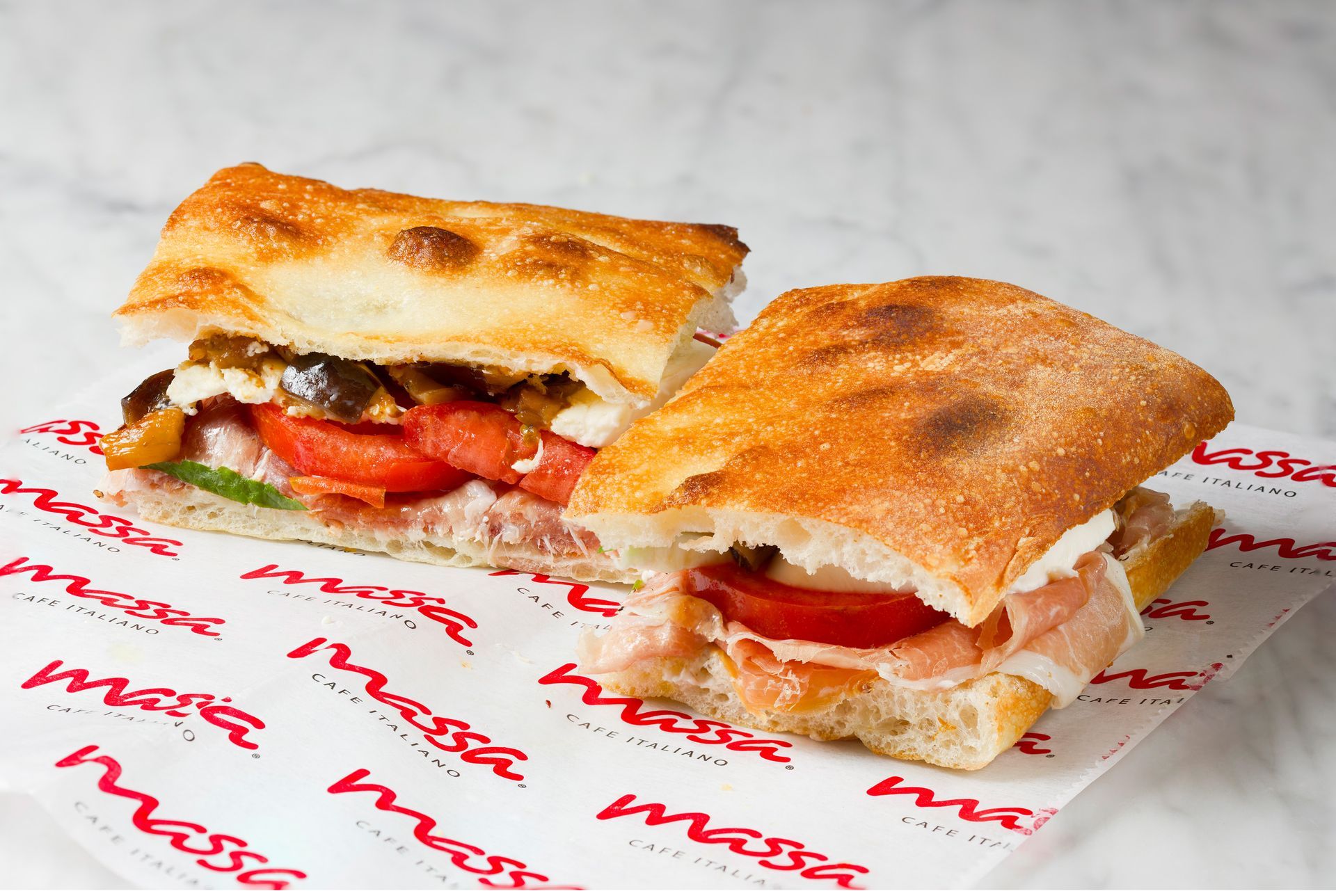 Two sandwiches are sitting on a piece of paper that says massa