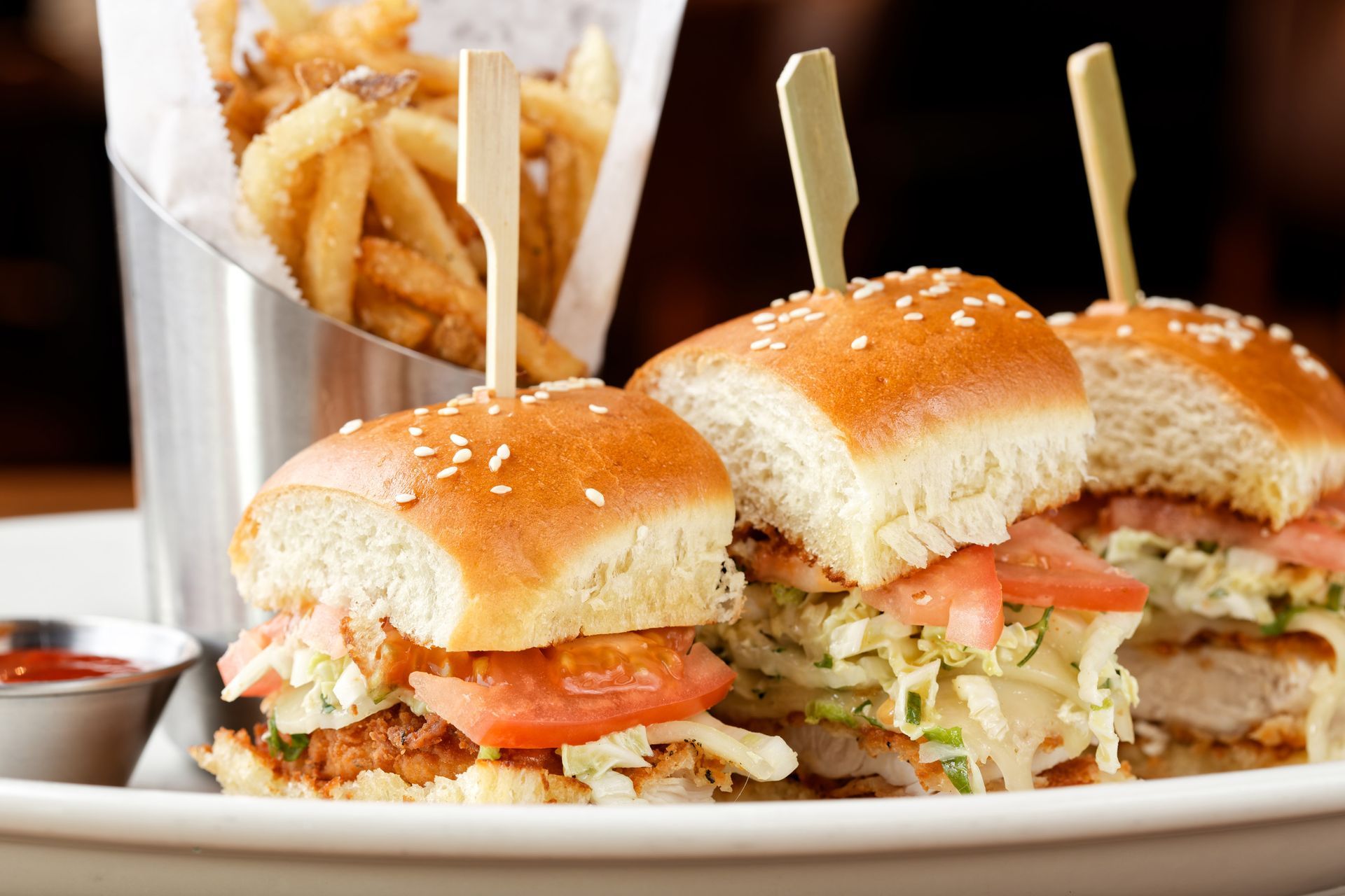 A white plate topped with three sandwiches and french fries