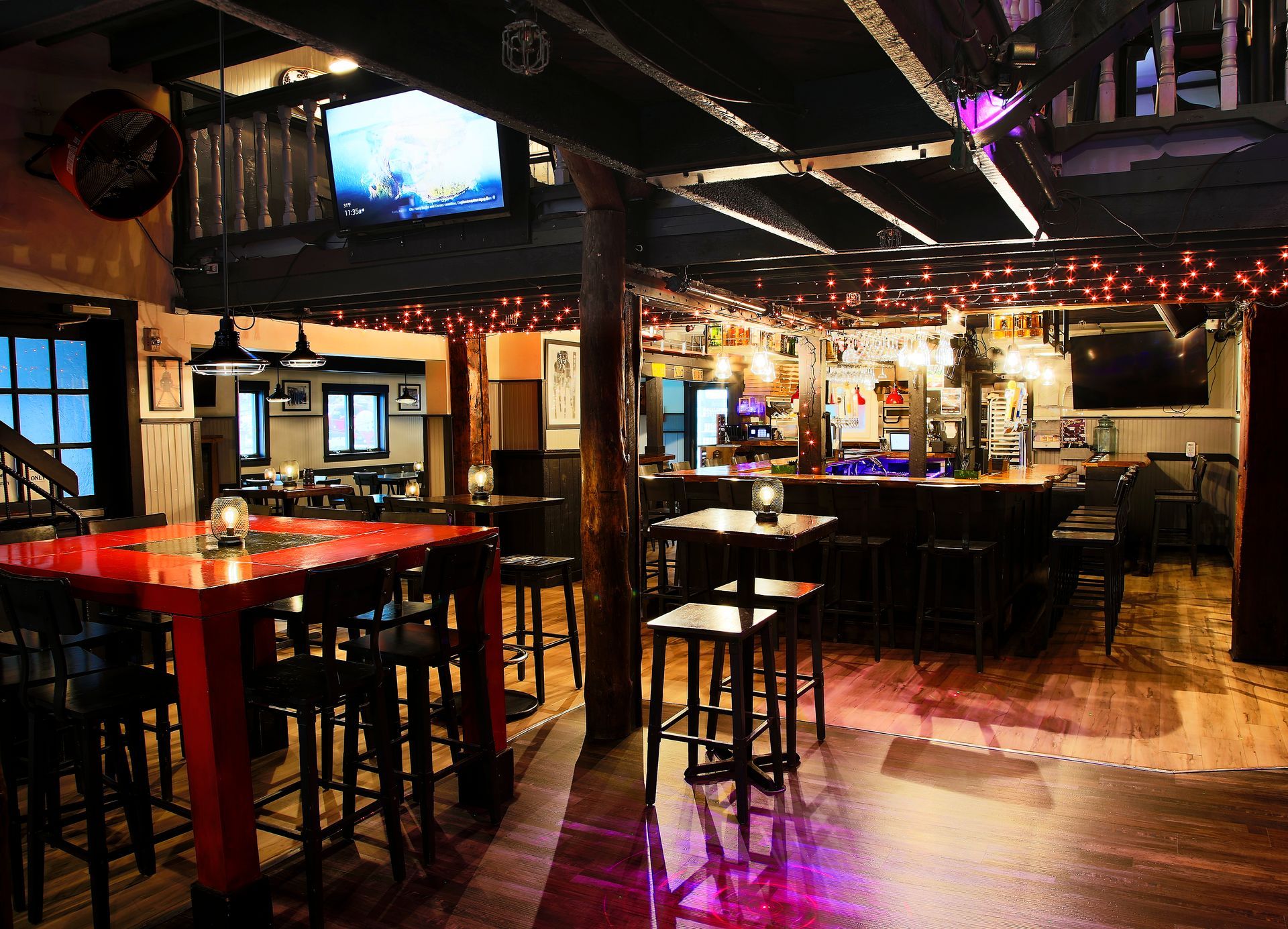 A bar with tables and stools and a tv on the wall