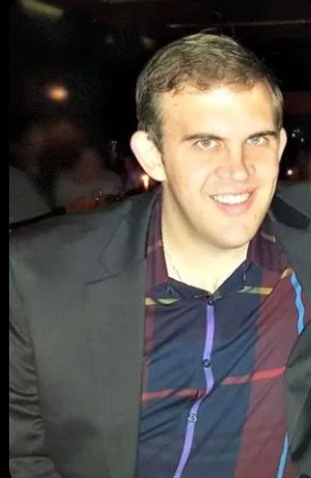 A man in a suit and striped shirt is smiling for the camera.