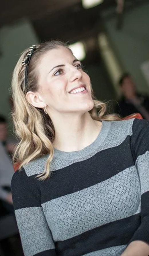 A woman in a striped sweater is smiling and looking up.