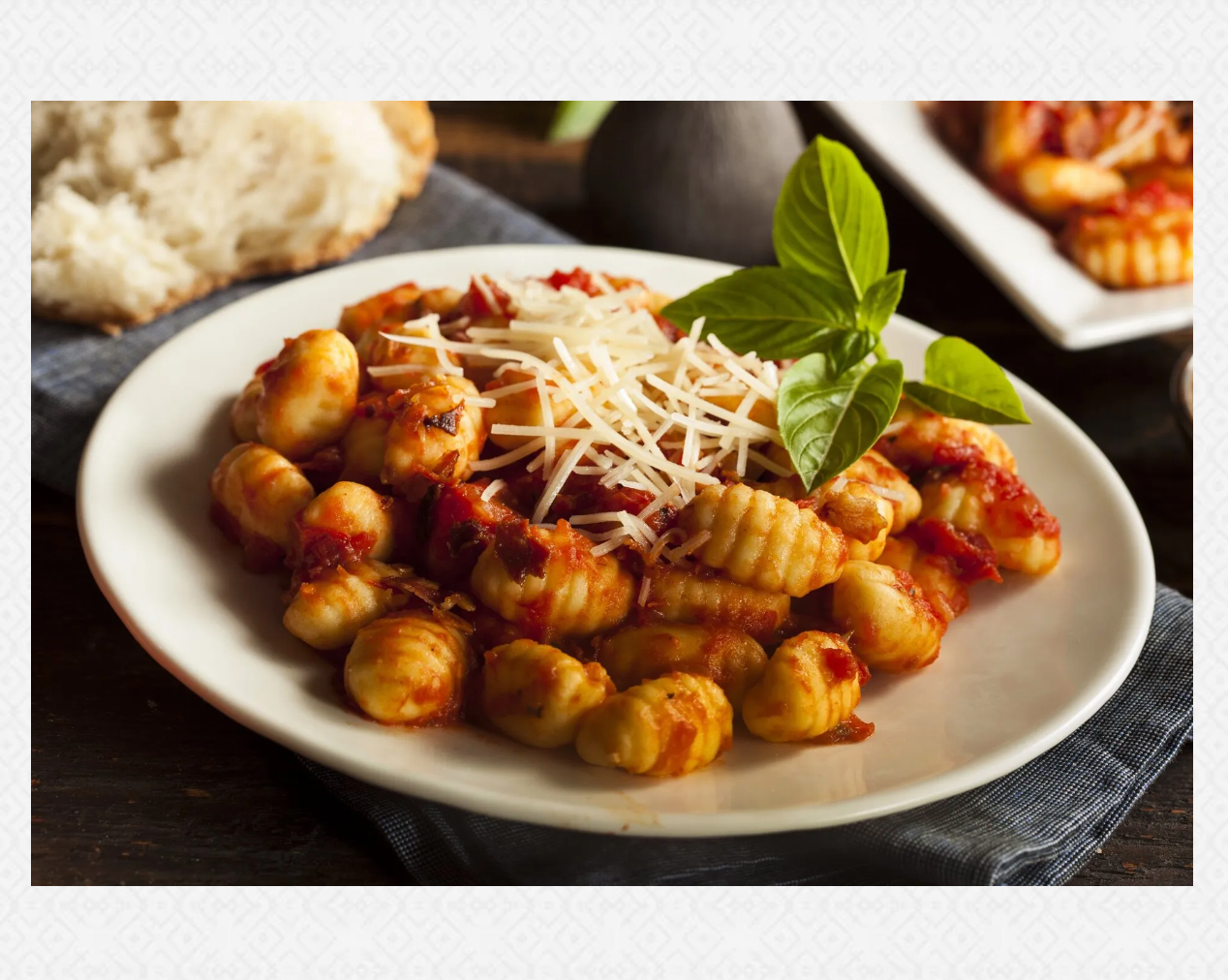 A white plate topped with gnocchi and tomato sauce