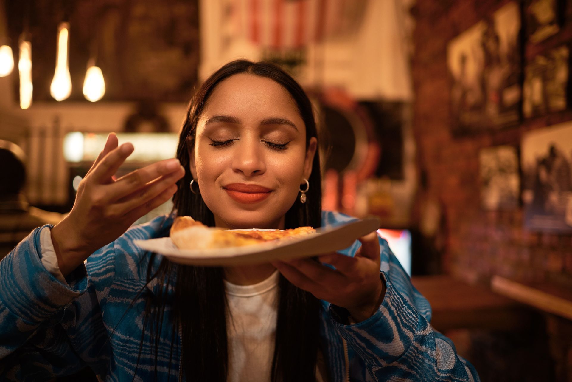 A woman is eating a slice of pizza in a restaurant.