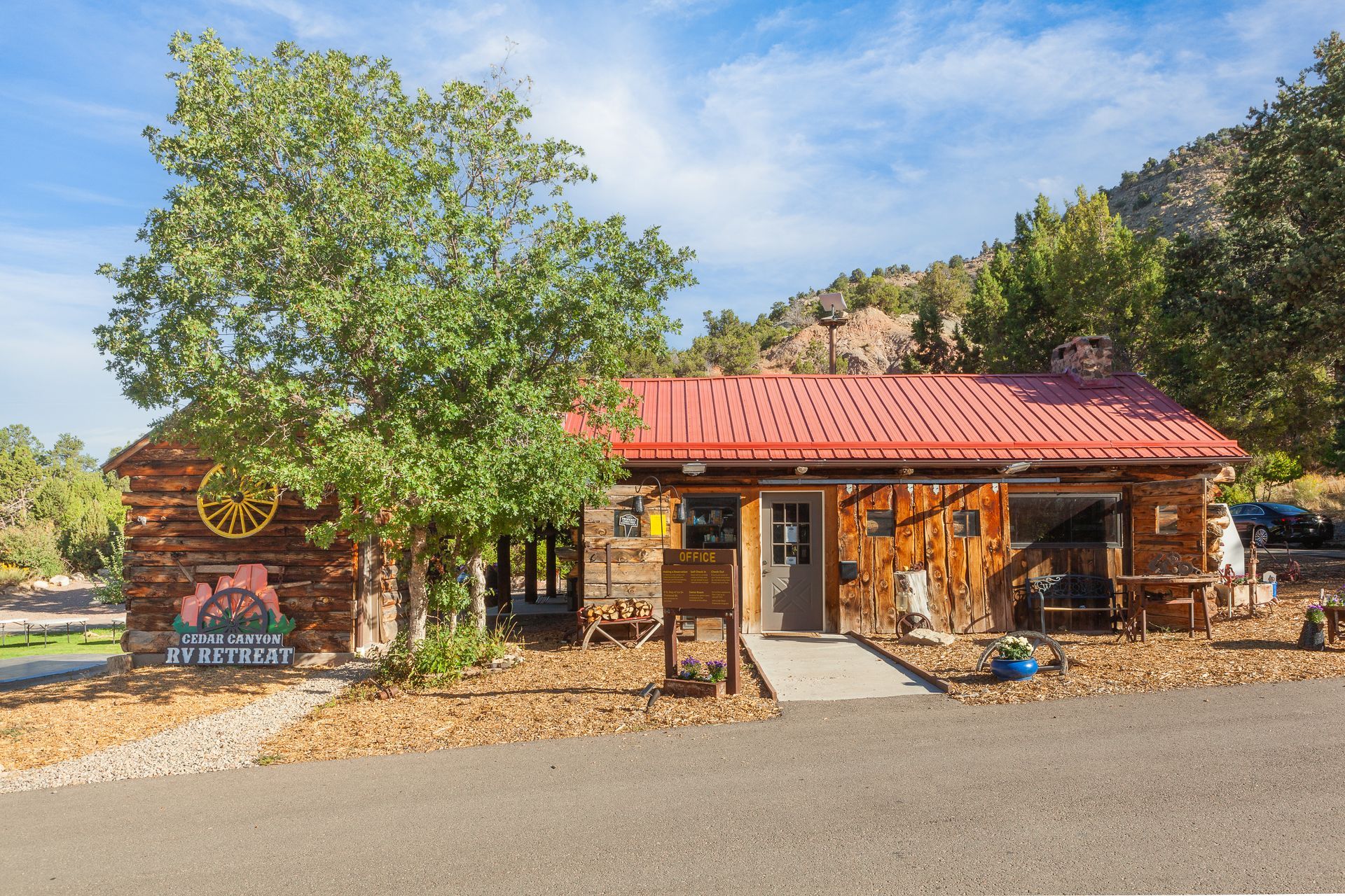 A small wooden building with a red roof and trees in front of it.