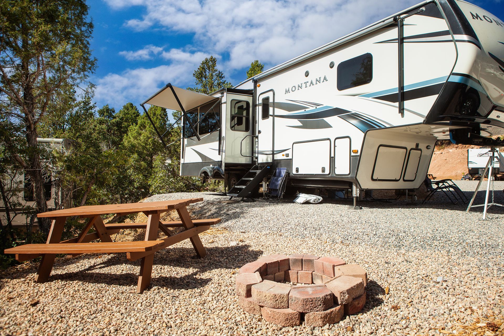 A rv parked next to a picnic table and a fire pit.