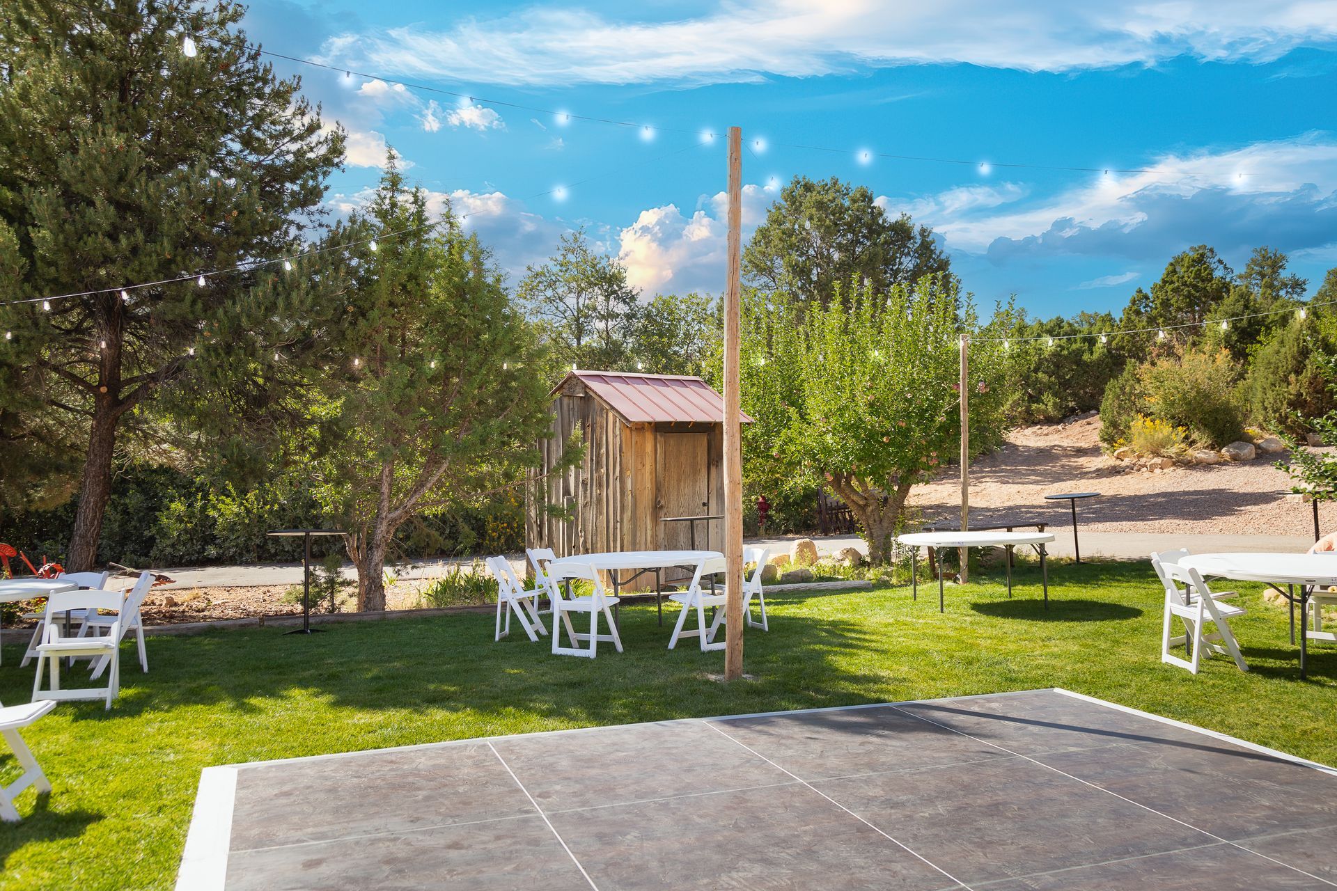 There is a dance floor in the middle of the grass with tables and chairs.