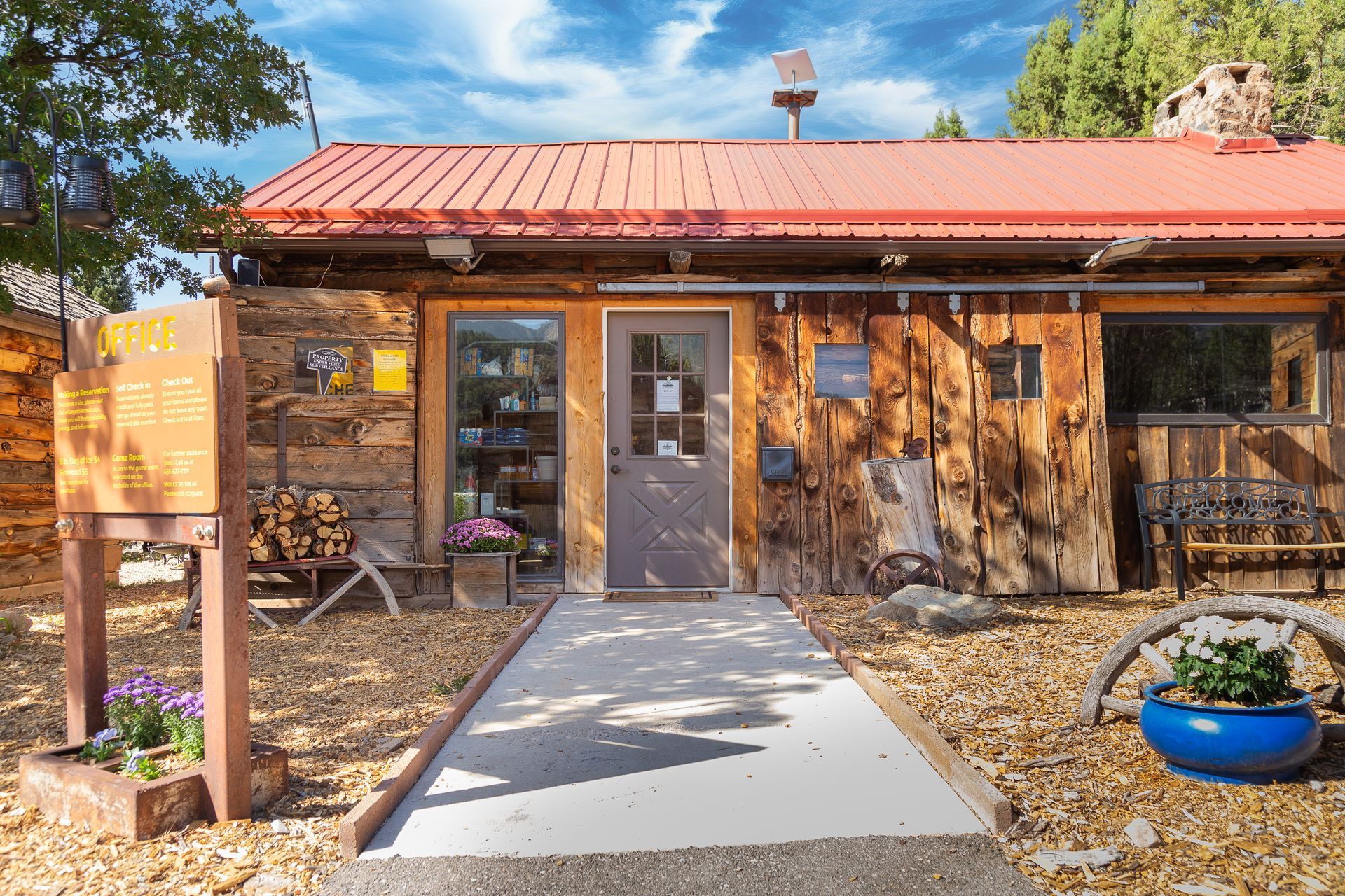 A wooden house with a red roof and a sign in front of it.