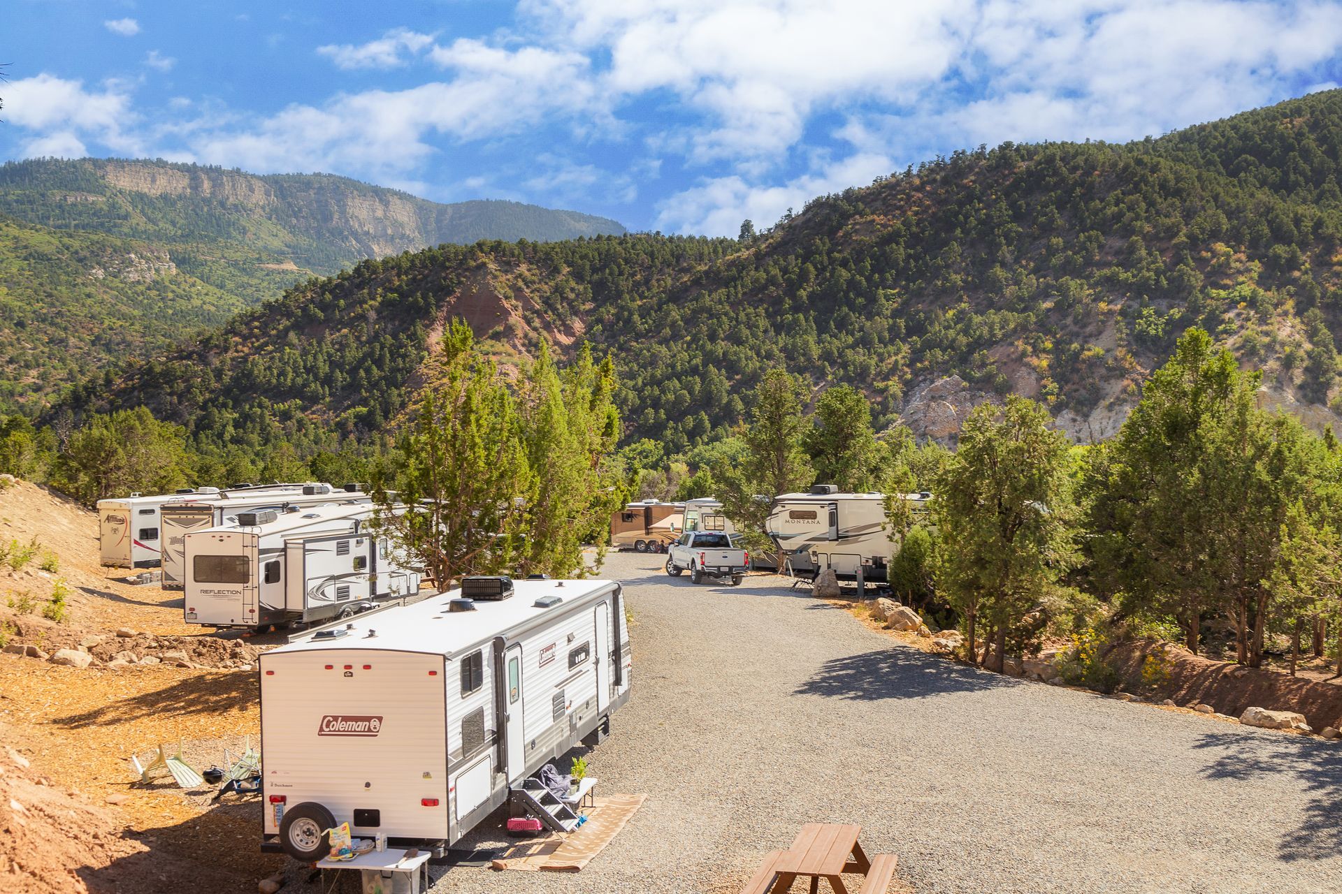 A row of rvs parked on the side of a dirt road in the mountains.